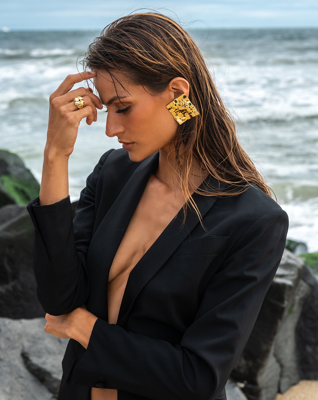 Model in black wearing Woven Square Earring with a backgroud of a beach