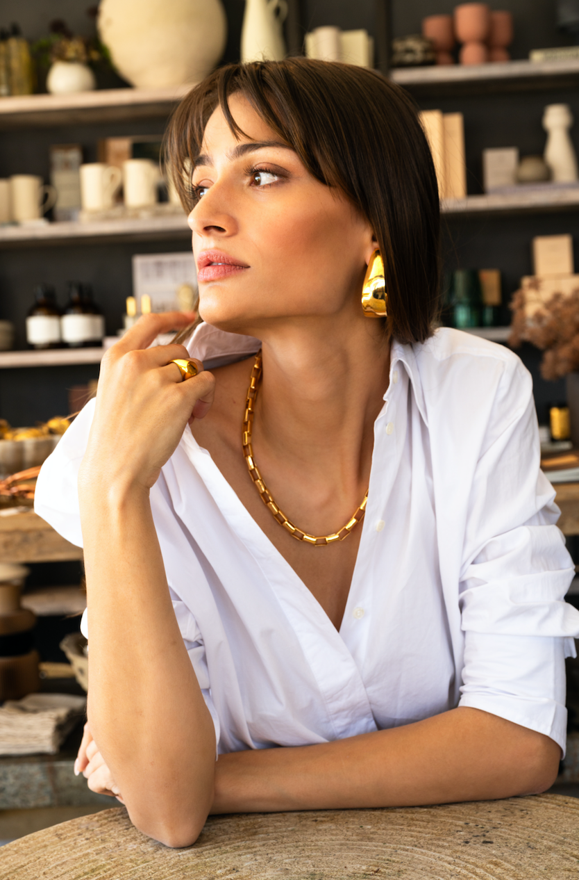 Model in white wearing gold necklace and ring