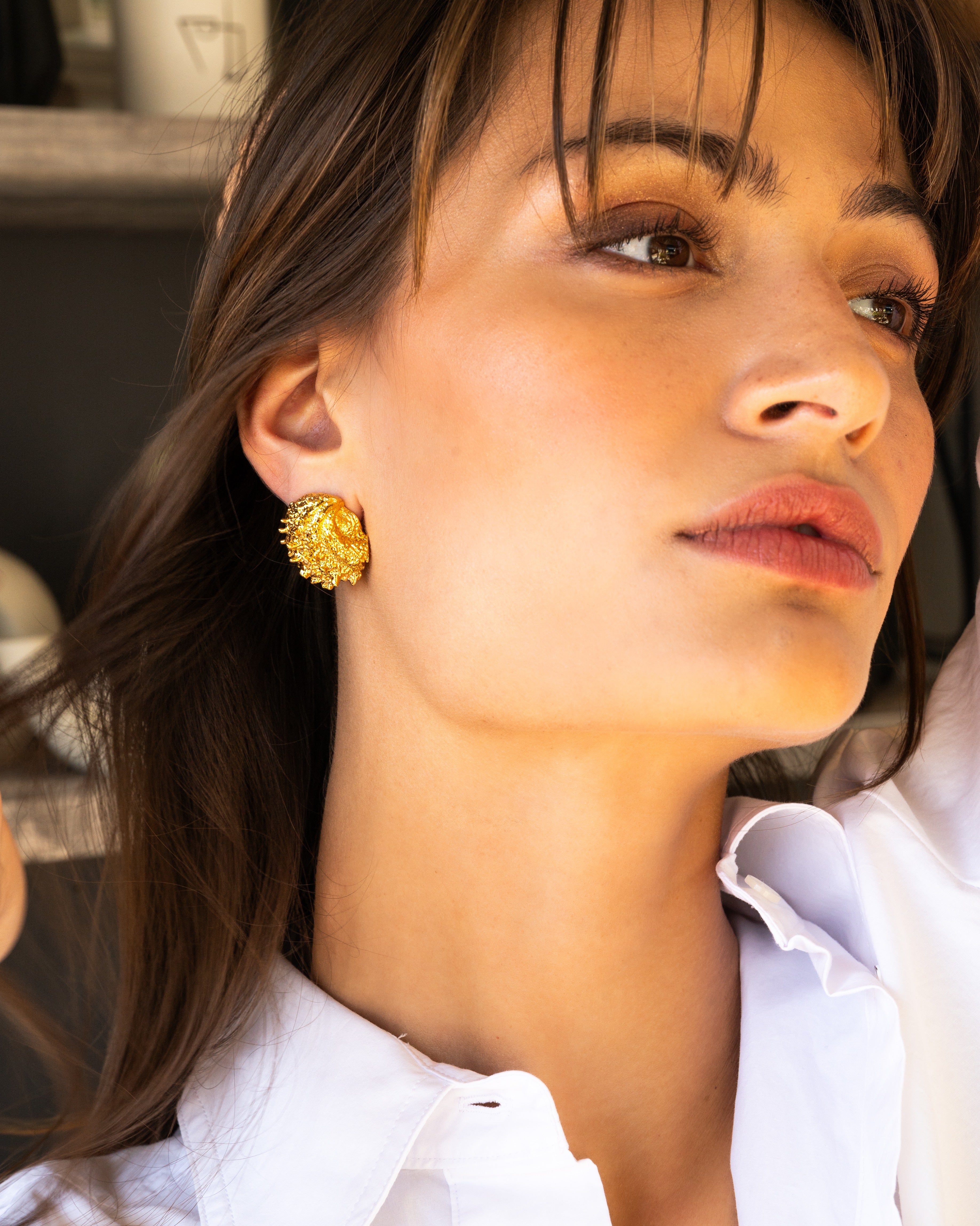 Model in white wearing Small Shell Earring, alternate angle.